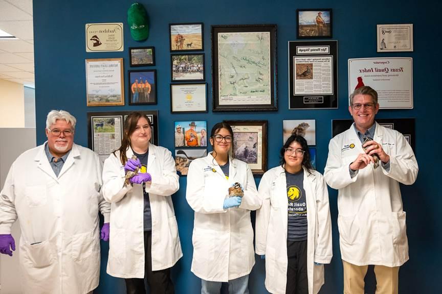 A group of faculty and student holding quail birds in there hand while smiling.