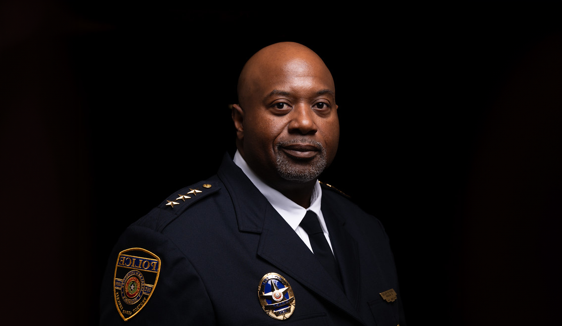 Against a black background, Chief Vaughn smiles slightly, wearing his formal police uniform and badge.